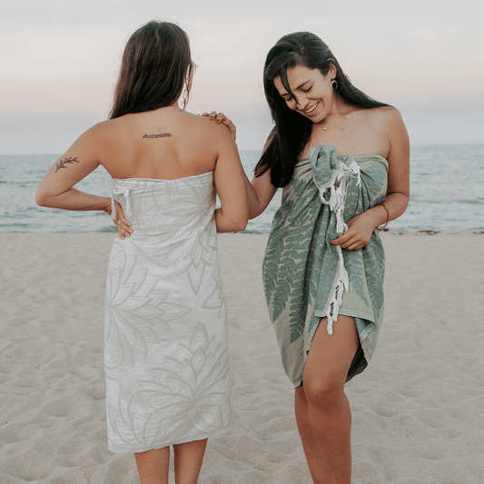 Two smiling women on the beach wearing Turkish towels