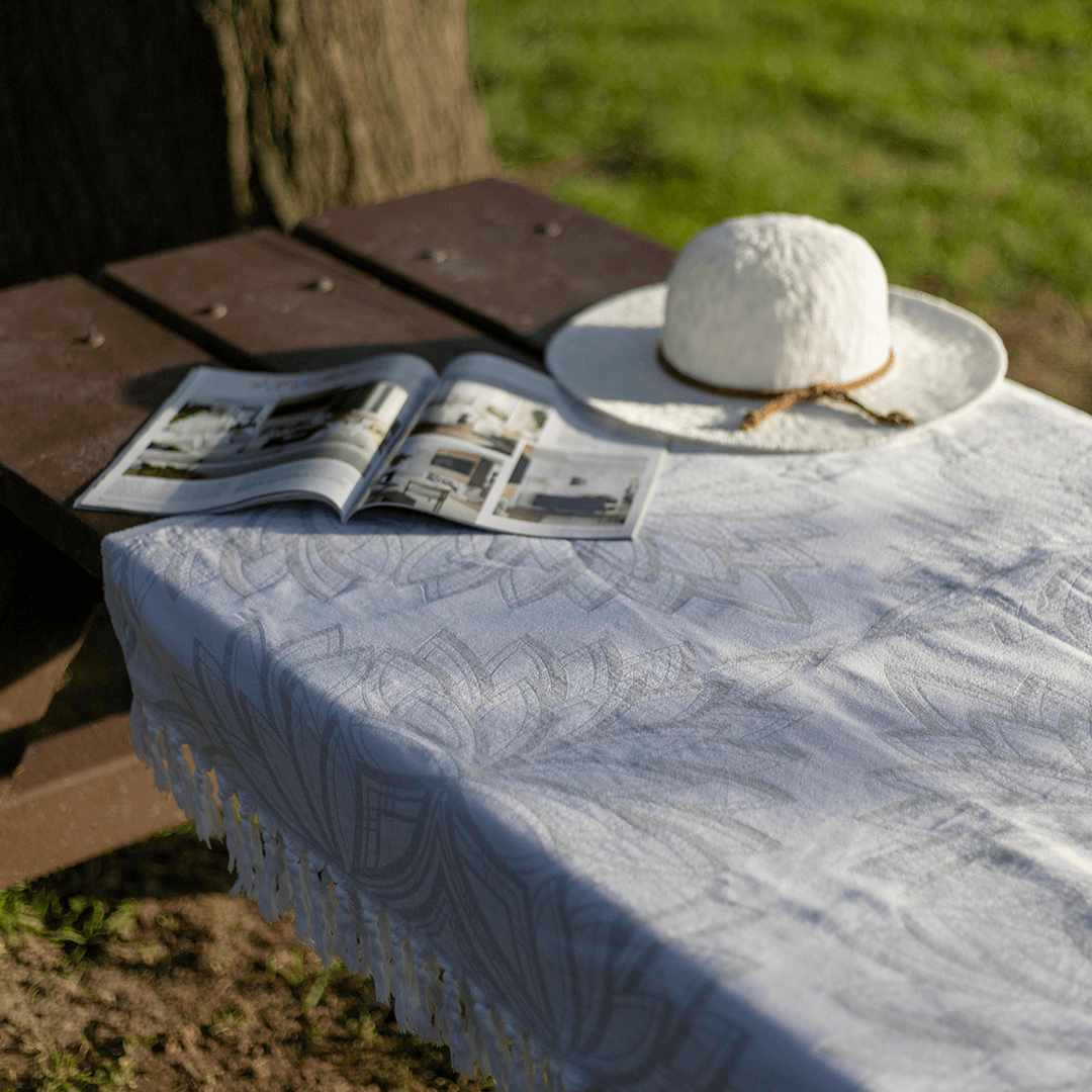 A Lotus designed Turkish towel used as a table cloth with a hat and magazine on top.