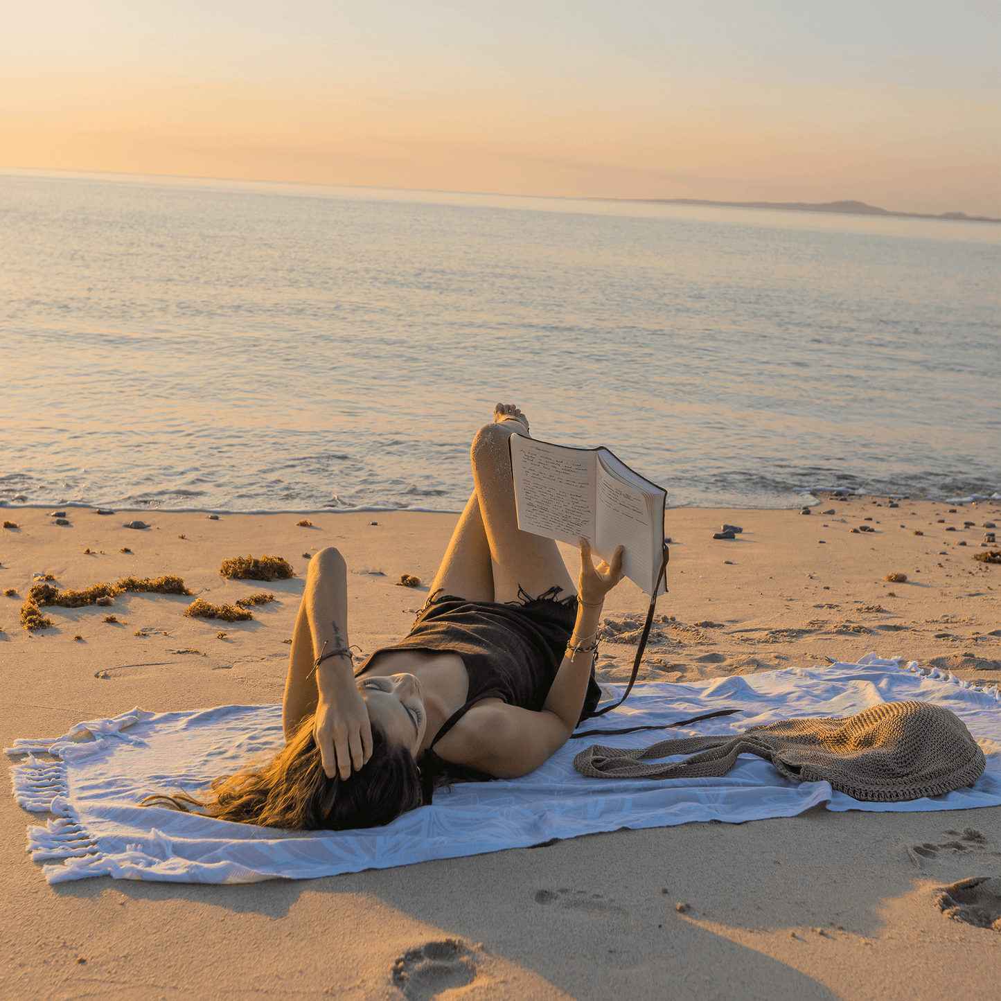 Woman at the beach reading on a Turkish towel