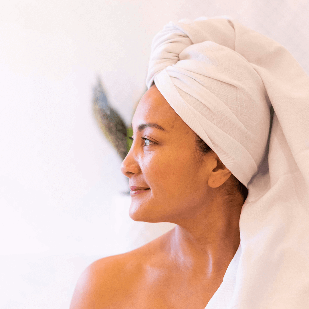 Smiling woman in a white Turkish towel in the bath