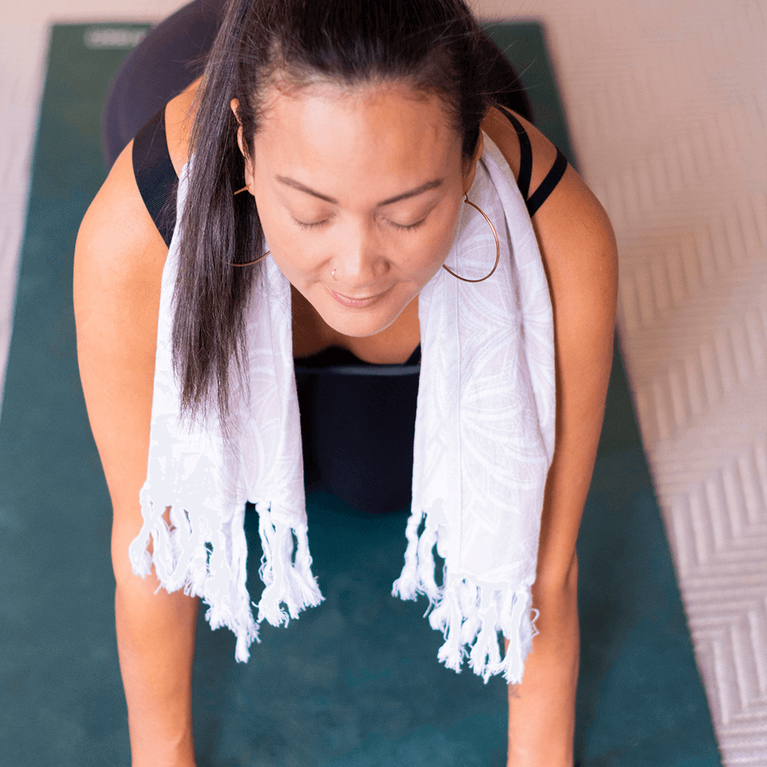 Happy woman using an oat and white Turkish hand towel for yoga practice
