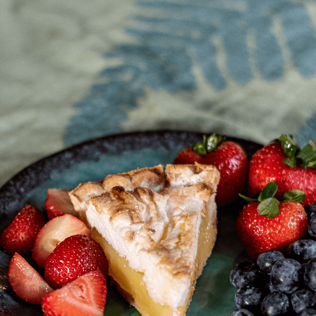 Green Turkish towel used as a tablecloth with strawberries blueberries and pie