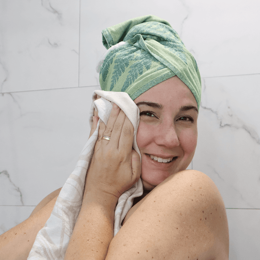Smiling woman uses Turkish towel in the bath for hair and face