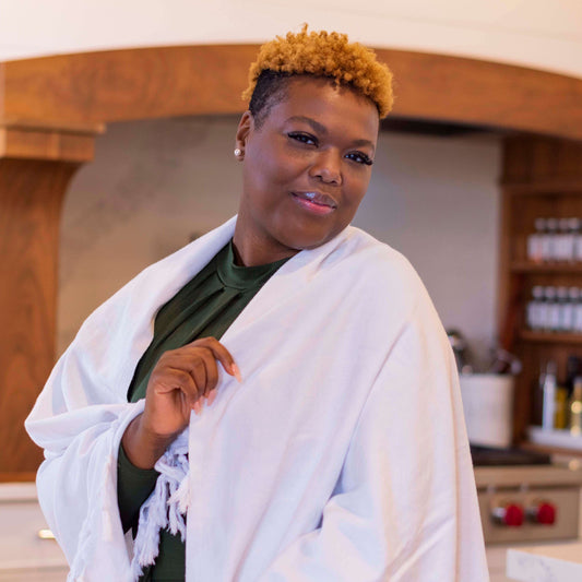 Black woman wearing a white Turkish towel as a shawl, smiling in a luxury home