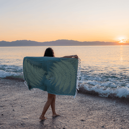 Woman on the beach with her Turkish towel. Luxury beach, travel essential. Sunset.