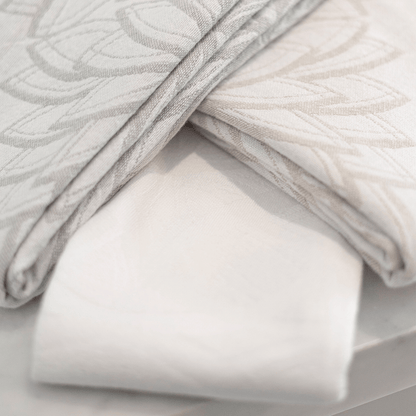 White and grey pomp and sass Turkish towels folded in a diamond shape overlapping.