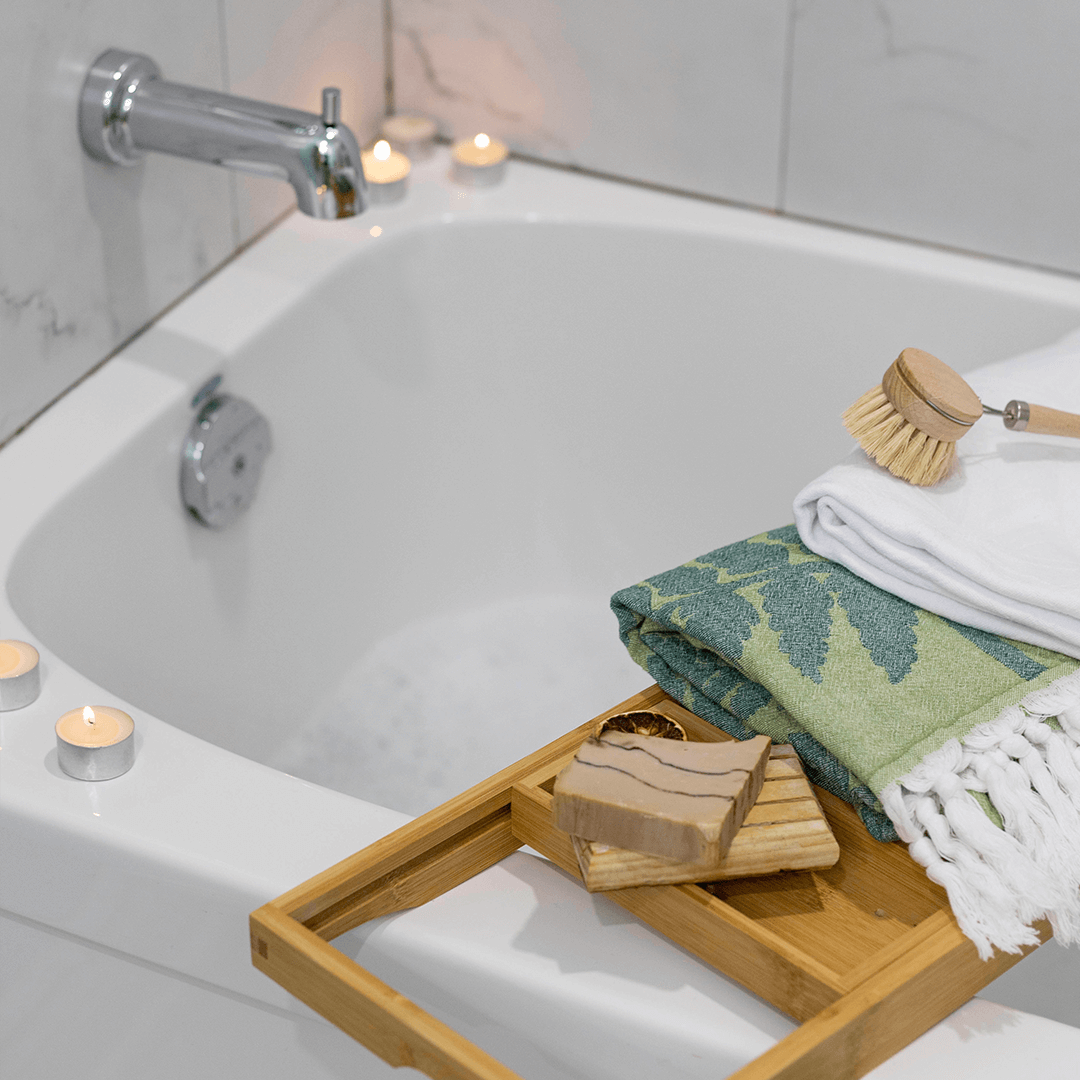 A green fern and white Pomp & sass towel placed over a bathtub. 