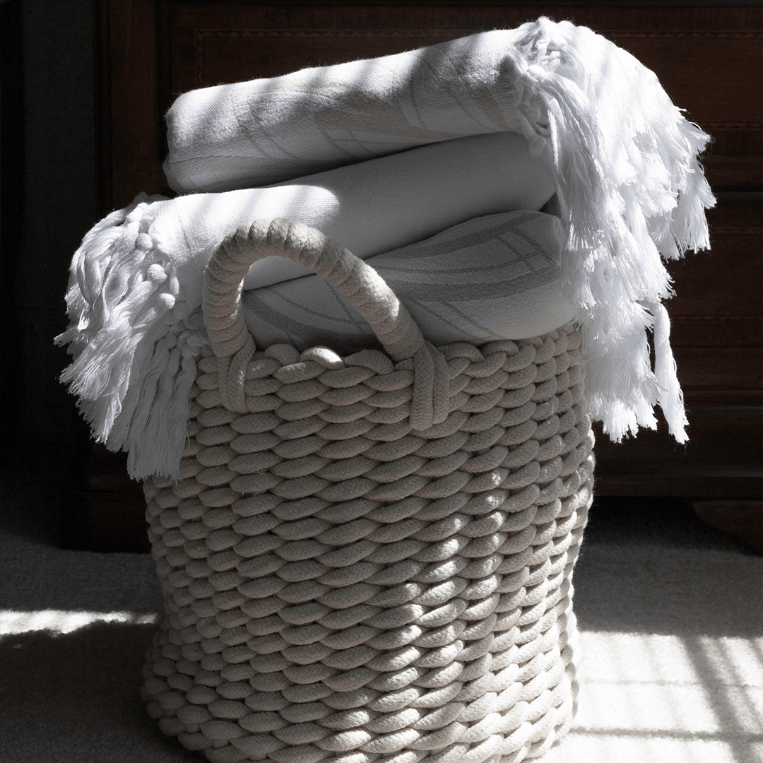 A basket of folded white and cream coloured Turkish towels. 