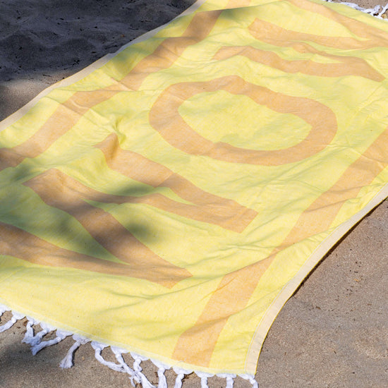 Yellow and orange Turkish cotton towel at the beach. Sand free.