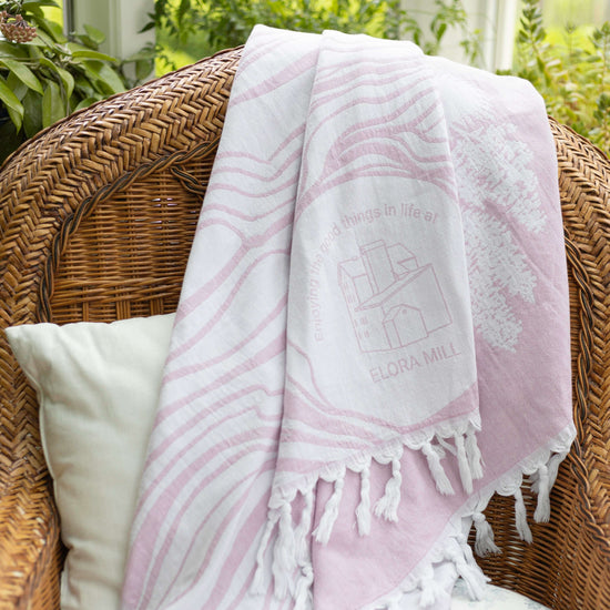 Pink and white Elora Mill Spa towel depicting the tooth of time and waterfall.