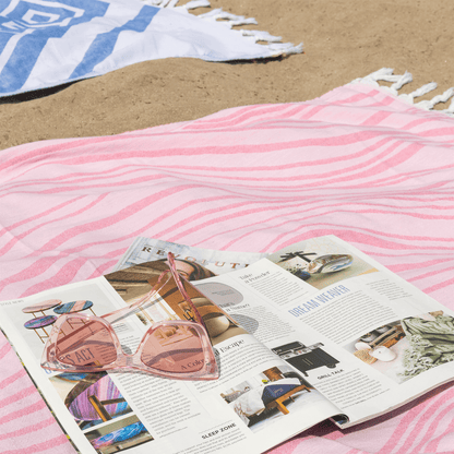 Pink Turkish towel on the beach with an open magazine