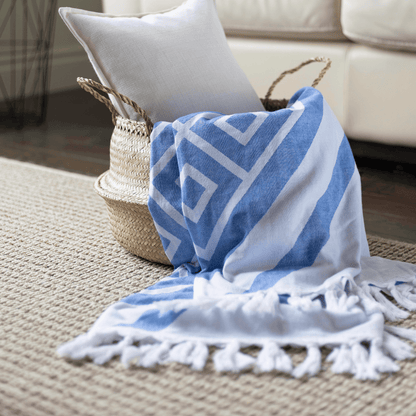 Blue and white Turkish towel overflows basket. It's being used as a decorative throw blanket