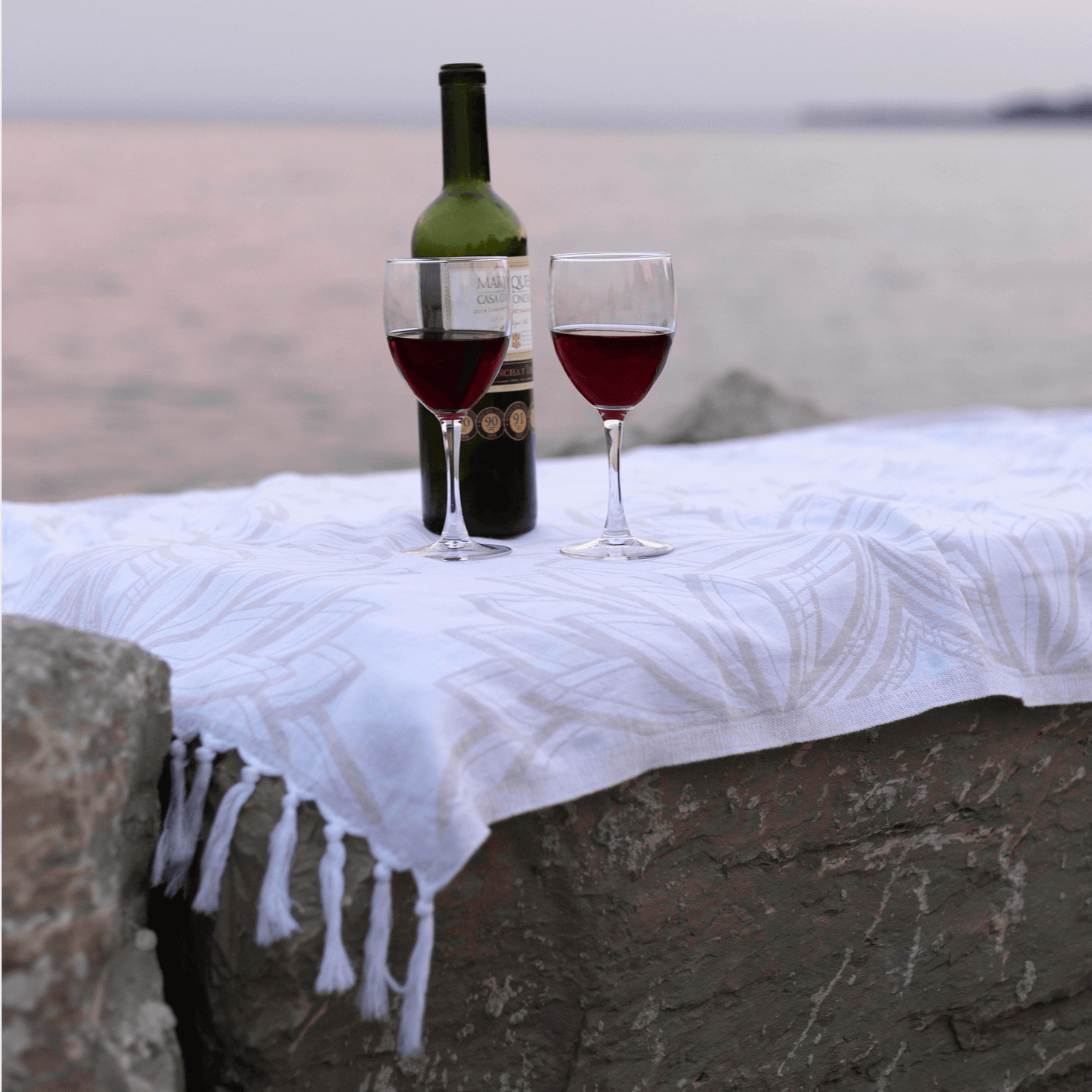 Turkish towels used as a picnic blanket neat the water with wine
