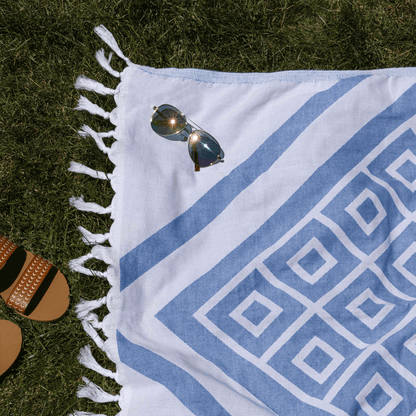 Blue and white Turkish towel used as a picnic blanket on summer grass