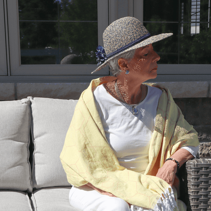 A senior woman used a honeycomb yellow Turkish towel as a shawl while sitting outside