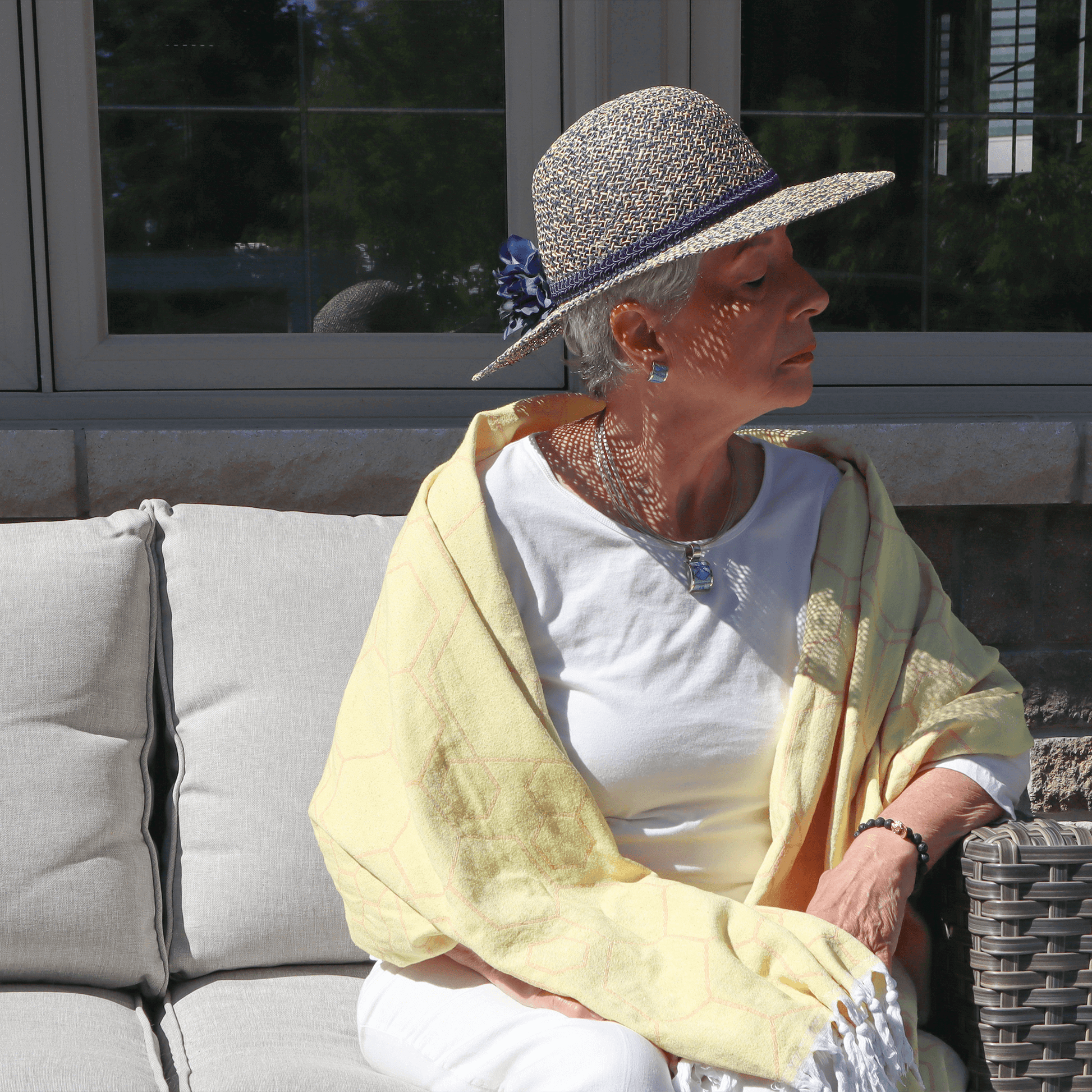elegant senior woman outside summer using a yellow Turkish towel as a shawl