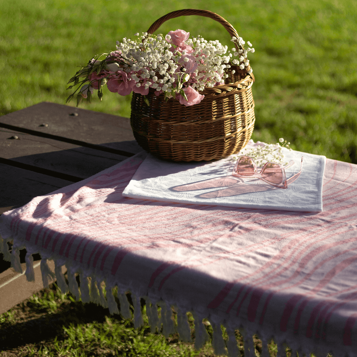 Pink stripped Turkish towel used as a picnic tablecloth outside summer