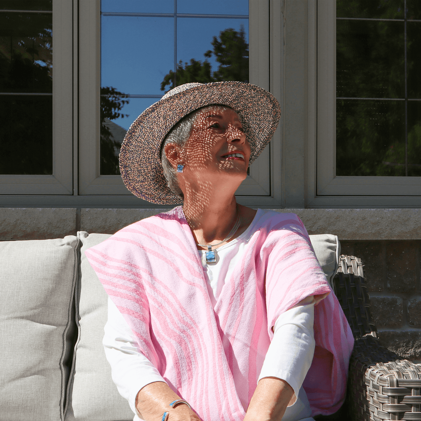 Senior woman sits outside with a pink Turkish towel used as a shawl