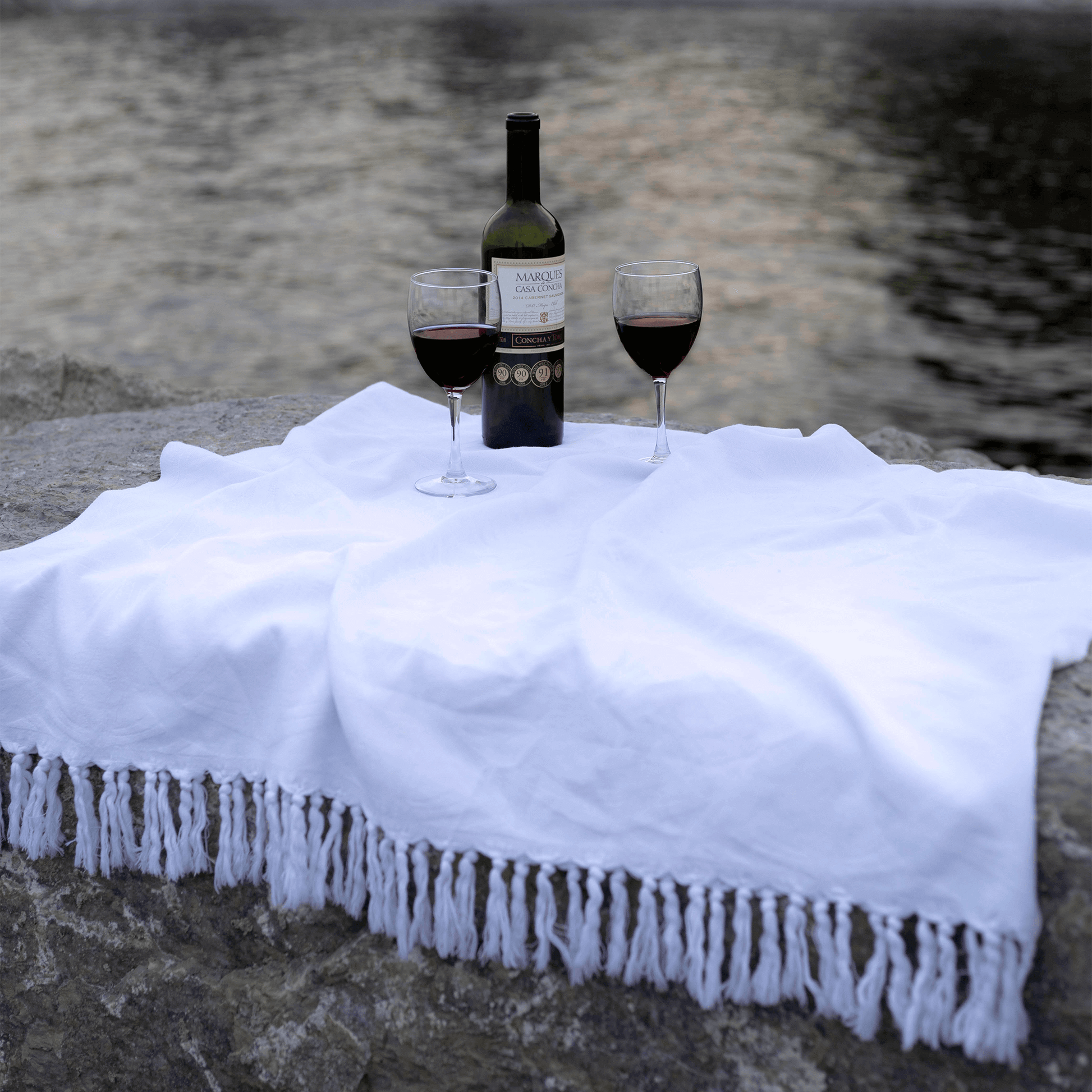 White Turkish towel near the water with wine glasses