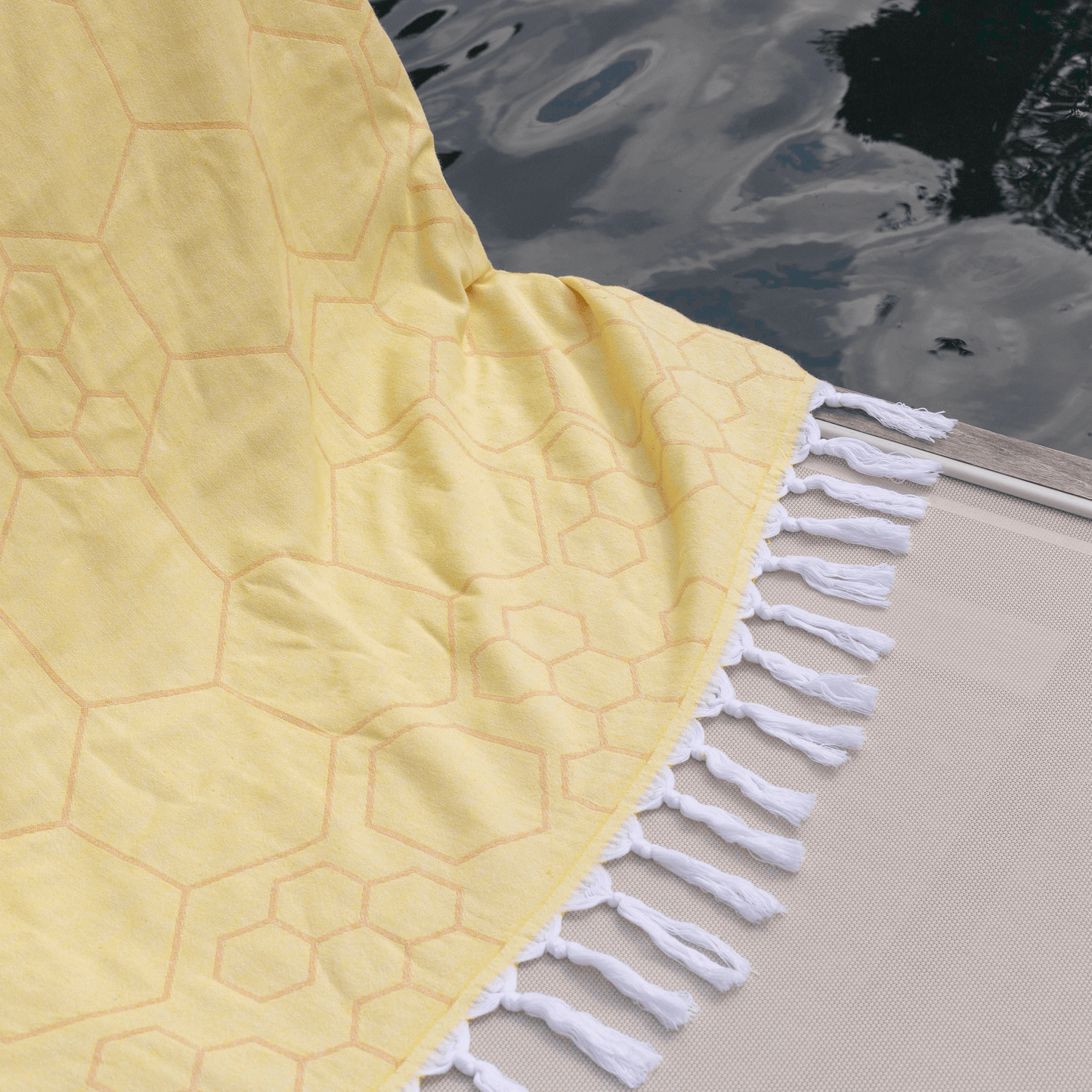 Close up of a yellow Turkish towels tassels next to a pool