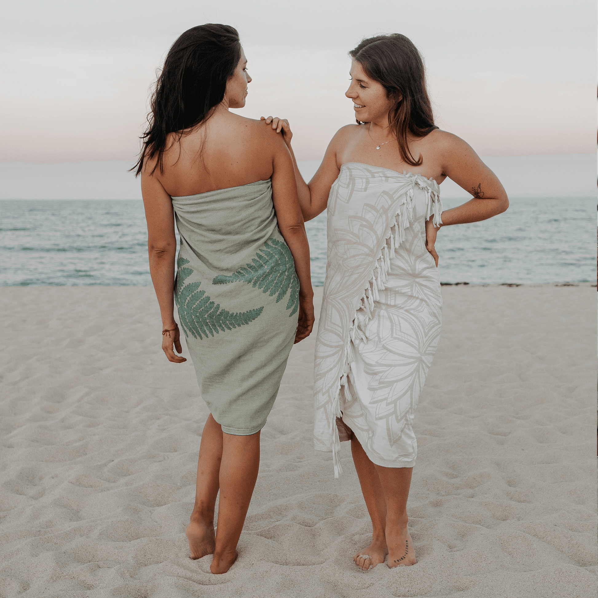 Two women at the beach using a Turkish towel as a sarong