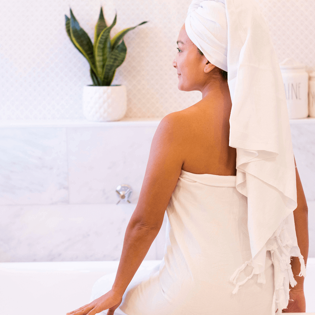 Woman in the bath wearing a white Turkish cotton towel by Pomp & Sass